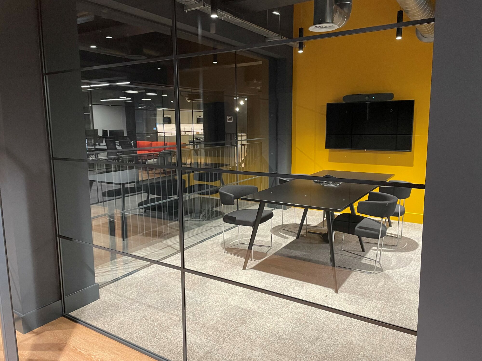 Beevers and Struthers meeting room with glass exterior walls, a yellow back wall and table and chairs inside.