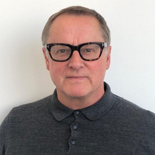 Portrait of John Boardman wearing glasses and a grey long sleeve polo
