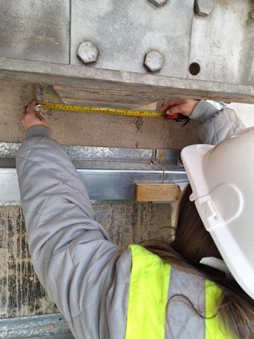 Georgia in a hard hat measuring at work