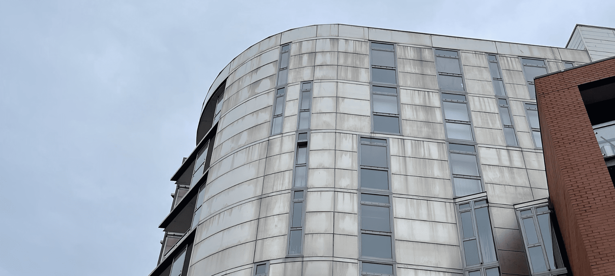 A close-up of the facade of an off white high rise residential building
