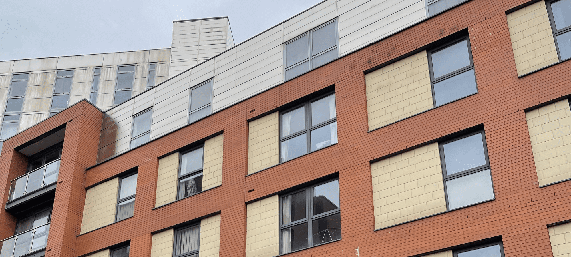 A close-up of the facade of a red brick high-rise residential building