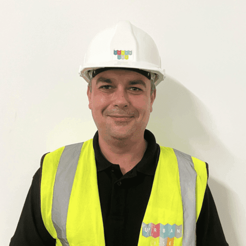 Headshot of Rob smiling. He is wearing an Urbanise branded hard hat and hi-vis vest.