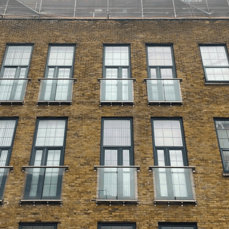 Front façade of The Exchange apartment building, with brickwork, windows and Juliette balconies.