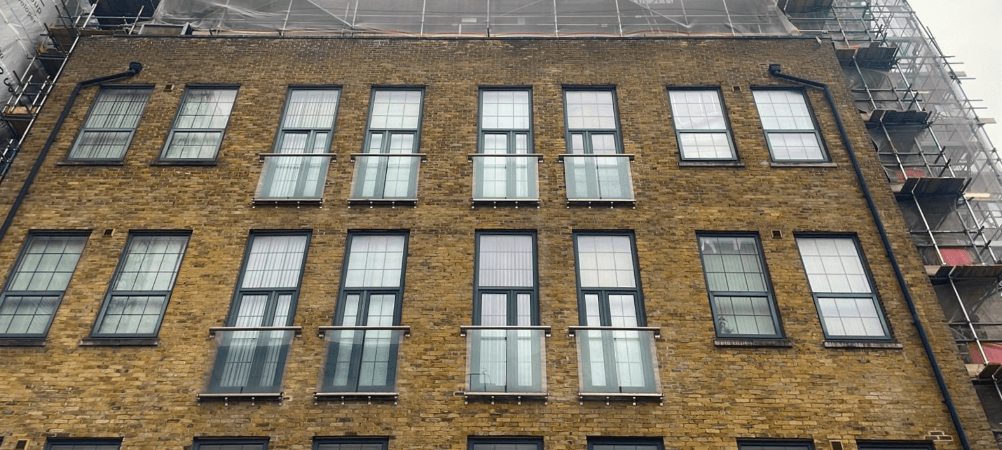 Front façade of The Exchange apartment building, with brickwork, windows and Juliette balconies.