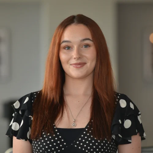 Headshot of Katie smiling. She is wearing a black and white polka dot dress.
