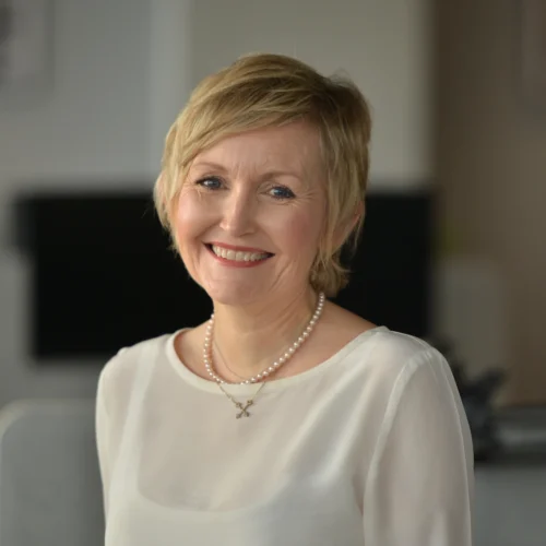 Headshot of Louise smiling. She is wearing a cream top.